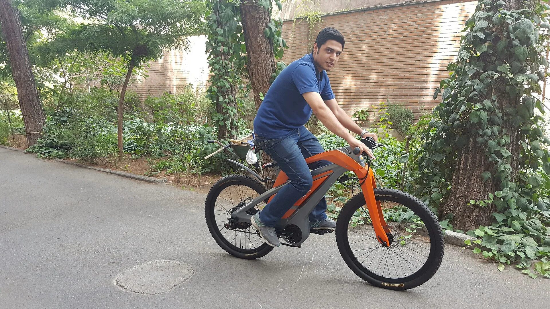 Teen rider on a kids e-bike waiting at a traffic light in a suburban bike lane